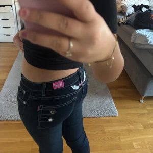 Low Mörkblå jeans med vita sömmar - Snygga mörkblå jeans från Hollister med vita kontrastsömmar och dekorativa knappar på bakfickorna. Jeansen har en tight passform och är lågmidjade, vilket ger en modern och stilren look. Perfekta för en avslappnad stil.