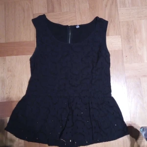 Svart ärmlös topp från ONLY - Snygg svart ärmlös topp från ONLY med spetsdetaljer och dragkedja i ryggen. Perfekt för en stilren look med en touch av elegans. Passar bra till både jeans och kjol.