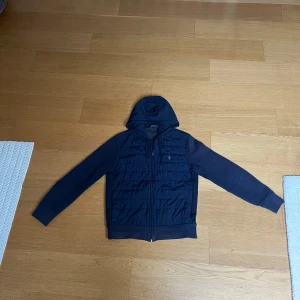 Mörkblå jacka med huva från Polo Ralph Lauren - Snygg mörkblå jacka med huva och dragkedja framtill. Jackan har långa ärmar och en quiltad design på framsidan. Storlek M skrev om ni har flera frågor! 🙌🙌