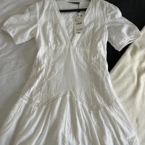 Vit klänning - Vit klänning med broderier och spets. Storlek M men passar S också . Aldrig använd och lappen kvar