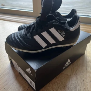 Adidas Copa Mundial fotbollsskor - Klassiska Adidas Copa Mundial fotbollsskor i svart och vitt. Tillverkade i skinn med snörning och rund tå. ALDRIG ANVÄNDA!🙃 Skinnet i skorna bidrar till att formas runt foten och minimerar skavsår mm. Köpt höst 2024 men aldrig använda, Nypris 1599 och säljer för 700kr! Men pris går att diskuteras. Kontakta vid fler frågor eller funderingar!