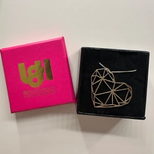 Silverfärgat halsband med hjärta från L8Hasselblad - Snyggt silverfärgat halsband med ett geometriskt hjärta som hänge. Perfekt för att ge en modern touch till din outfit. Kommer i en rosa förpackning. I äkta silver och nypris på hemsidan är 750kr. 💕💕