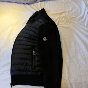 Moncler Cardigan - Köptes för ca 2 år sen, bra skick. Dragkedjan är tyvärr inte längre en Moncler kedja utan fick bytas ut mot en helsvart då den gick sönder. Annars är allt som det ska. Den är perfekt inför vår eller lite kallare sommardagar. Skriv om du har några frågor eller vill ha mer bilder, priset är ej hugget i sten. (Osäker på om den är äkta)