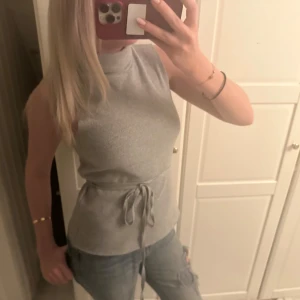 Grå ärmlös topp med knytband - Snygg grå ärmlös topp med knytband i midjan. Den är från Zara❣️