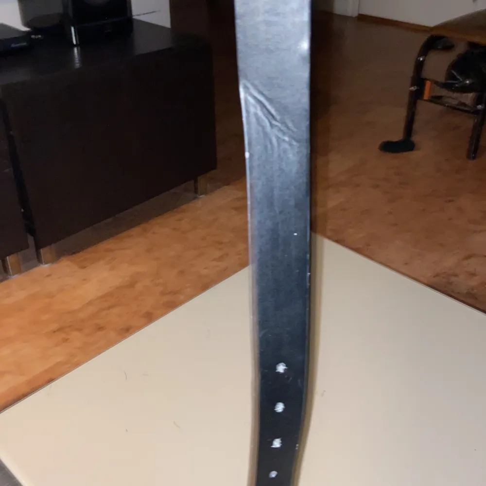 Snyggt svart bälte med ett stilrent silverfärgat spänne. Perfekt för att ge en elegant touch till din outfit. Bältet har flera hål för justering och passar de flesta storlekar.. Muu.