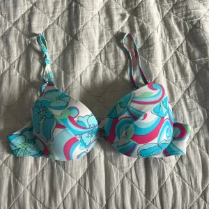 Färgglad blommig bikini - Säljer en färgglad bikini med blommigt mönster i turkos, rosa och vitt. Toppen har justerbara axelband och bygel för extra stöd. Bikinitrosorna har en klassisk skärning. Perfekt för sommarens stranddagar!