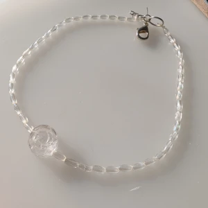 Transparent-ros halsband med pärlor - Säljer ett elegant transparent halsband med små pärlor och en större ros som detalj. Perfekt för att ge en subtil glans till din outfit. Halsbandet har ett enkelt lås i metall och är handgjort!