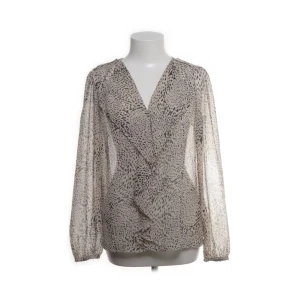 Mönstrad blus från Vila - Säljer en luftig och transparent blus från Vila i beige med svart prickigt mönster. Blusen har omlott-design, långa ärmar med resår vid handlederna och v-ringad hals. Pris kan diskuteras💕