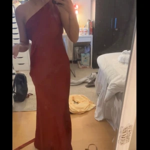 Vinröd one shoulder långklänning - Säljer en elegant vinröd långklänning med one shoulder-design och öppen rygg. Klänningen har en snygg omlott-detalj bak och är figurnära. Perfekt för festliga tillfällen eller balen. Kan skickas snarast sitter som en xs-s