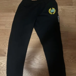 Svarta träningsbyxor med Hammarby IF-logga - Svarta träningsbyxor från Craft med Hammarby IF-logga på ena benet. Perfekta för dig som vill representera laget på träningen eller på fritiden. Byxorna har en enkel och sportig design.