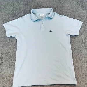 Ljus Blå LACOSTE Piké  - 📊 Färg~ LJUS Blå  Se bild 5 för bästa färg exemplet   📏 Storlek~ Small (S) (Kan även passa som XS)   📐 Mått~ Axel till axel~ 47CM Midja till hals~ 58CM  ♻️ Väldigt bra skick ⁉️NYPRIS 1000kr 📦 Postar Inom 24h!