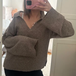Brun stickad tröja - Mysig beige stickad tröja med bred krage och v-ringning. Tröjan har långa ärmar och ribbade muddar vid ärmslut och nederkant. Perfekt för lager-på-lager och chill dagar. 🤎🤎🤎
