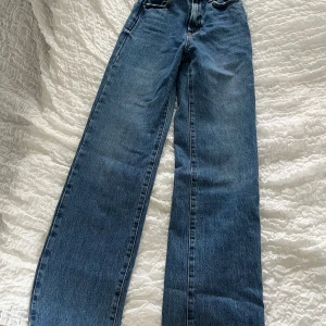 Blå wide leg jeans från Zara - Säljer ett par blå jeans från Zara med breda ben och klassisk femficksmodell. Jeansen har hög midja och stängs med knapp och dragkedja. Perfekta för dig som gillar en avslappnad och trendig stil.