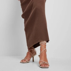 Vita klackskor från NA-KD - Eleganta beige klackskor från NA-KD med smala remmar och knytning runt ankeln. Skorna har en fyrkantig tå och en stilren design som passar perfekt för festliga tillfällen.