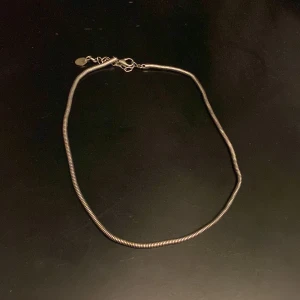 Halsband - Säljer ett stilrent silverfärgat halsband. Kedjan har en ormliknande design och är enkel att matcha med olika outfits. Perfekt för dig som gillar minimalistiska smycken.