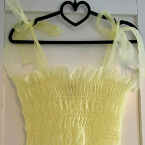 FRILL TOPP - Världens sötaste gula topp med volangkant nertill och smockad överdel. Toppen har rosetter som knyte vilket gör den så classy! Perfekt till påsk eller festliga sommarkvällar. Oanvänd!✨✨🍋💛🐝🌼🌼Passar xs/s