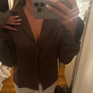 Brun satinskjorta från Gina Tricot - Säljer en brun skjorta i satin från Gina Tricot. Den har ett litet spänne på insidan, sen är den helt öppen utan knappar. Storlek 38, köpte för 399, säljer för 299. Lappen kvar och oanvänd!