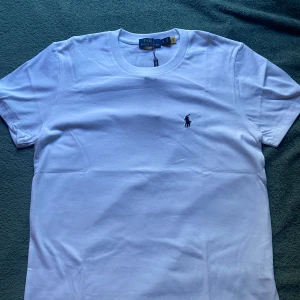 Ralph Lauren T- shirt - Klassisk vit t-shirt från Polo Ralph Lauren med broderad logga på bröstet. T-shirten har rund halsringning och korta ärmar. Perfekt basplagg med stilren design och mjukt bomullsmaterial. Storlek M men kan funka som S också. Skriv privat vid frågor!