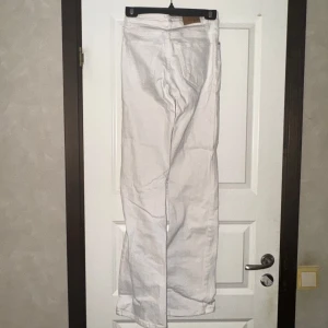 Vita bootcut jeans - Säljer ett par vita jeans med bootcut passform. Byxorna har klassisk femficksdesign och stängs med dragkedja och knapp. Perfekta för dig som vill ha en stilren och tidlös look.