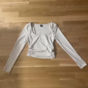 Beige långärmad topp från SHEIN - Säljer en beige långärmad topp från SHEIN i storlek S. Toppen har en fyrkantig ringning och snygg rynkdetalj på sidan. Materialet är mjukt och stretchigt, perfekt för en stilren look.