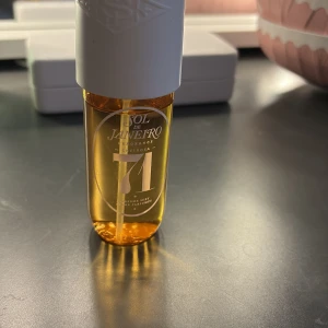Sol de Janeiro 71 Perfume Mist - Parfymmist från Sol de Janeiro med doft av karamelliserad vanilj, rostad macadamia och tonkaböna. Flaskan är genomskinlig med gyllene vätska och har ett vitt lock. Perfekt för dig som gillar söta och varma doftnoter.