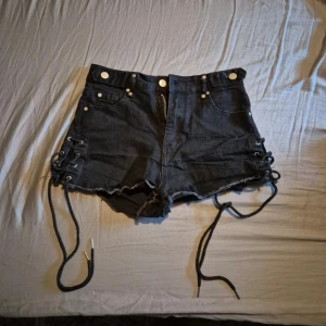 Svarta högmidjade shorts str S - Högmidjade svarta jeans shorts med knytnings detaljer på sidorna, storlek S  Använda enstaka gånger Fickor fram och bak, alla funkerande. Blixtlåset funkar bra. Väldigt stretchiga!  Nypris:159kr  Kläderna rollas innan dom skickas då katt finns i hemmet!  #jeansshorts #svartajeansshorts #blackjeansshorts #wilmabookss #wilmabooksstorleks