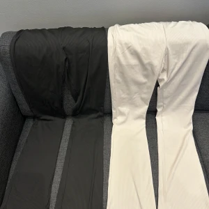 Ribbade byxor från Divided H&M i svart och vitt - Två par ribbade byxor från Divided H&M, ett par svarta och ett par vita. Byxorna har elastisk midja och är tillverkade i stretchigt material för en bekväm passform. Perfekta för en avslappnad stil.