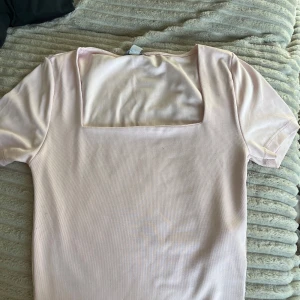 Ljusrosa topp med fyrkantig ringning från new yorker - Säljer en ljusrosa topp från New yorker med korta ärmar och snygg fyrkantig ringning. Säljer då den inte kommer till användning!