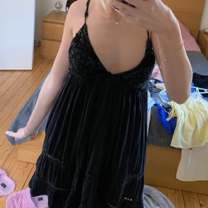 Svart klänning med spetsdetaljer från Urban Outfitters - Supersöt svart klänning från Urban Outfitters med tunna axelband och vacker spets upptill. Klänningen har en luftig passform och fina volangdetaljer nertill. Perfekt för varma dagar eller när du vill känna dig extra fin.