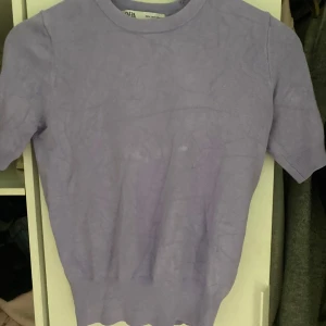 Ljuslila topp från Zara - Säljer en ljuslila topp från Zara med korta ärmar och rund halsringning. Toppens material känns mjukt och stretchigt, perfekt för en stilren och enkel look. Passformen är normal och toppen är enfärgad utan mönster.