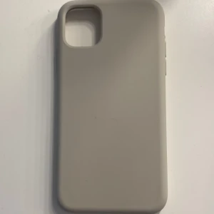Grå mobilskal, oanvänt - Säljer ett stilrent beige mobilskal med matt finish. Skalets design är enkel och clean, perfekt för dig som vill ha ett diskret skydd till mobilen. Passar till en modell med större kameraöppning. Har aldrig använt