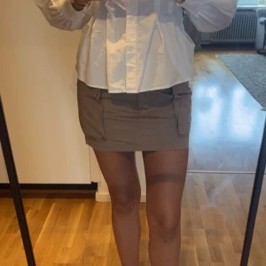 Beige minikjol med fickor från H&M - Säljer en beige minikjol från H&M med två stora fickor framtill och dragkedja. Perfekt för dig som gillar en enkel och stilren look.