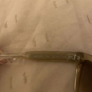 Beige solglasögon från CHIMI - Snygga solglasögon från CHIMI i beige transparent plast med fyrkantig form och bruna tonade glas. Kommer med originalfodral och putsduk. Perfekta för att lyfta din stil med en modern touch.