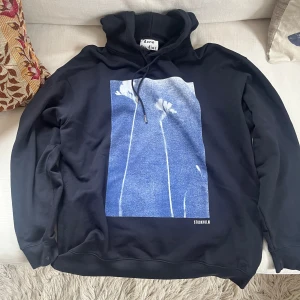 Acne Studios hoodie - .Snygg svart hoodie från Acne Studios med ett unikt blått och vitt blommönster på framsidan. Texten 'Nurture' är tryckt på baksidan. Perfekt för en stilren och modern look. Hoodien är något större i passform så skulle säga att den passar mer m l snarare än s. Nypris ligger på strax över 4500kr. Vid några frågor är det bara att höra av sig. Priset ej hugget i sten. Mvh August. 