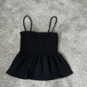 Svart smockad linnetopp med tunna axelband - Säljer en svart söt  linnetopp med smockad överdel och tunna axelband.😚💕