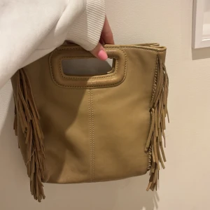 Beige maje väska - Säljer en beige maje väska. Väskan är i skin. Perfekt accessoar för att lyfta din outfit!TRYCK EJ PÅ KÖP NU.