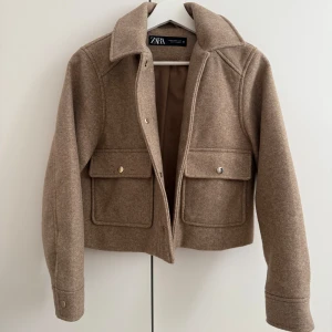 Beige jacka från ZARA - Säljer en beige jacka från ZARA. Jackan har stora fickor framtill med knappar, klassisk krage och är croppad i modellen. Perfekt för lager-på-lager och nu till våren. Endast testad och därmed i nyskick. 💛