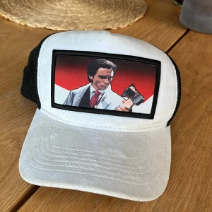 Vit och svart keps från Centauri med Psycho-motiv - Säljer en vit och svart velvet keps från Centauri med mesh baktill och justerbar snapback. Framtill finns ett tryck med motiv inspirerat av filmen American Psycho. Märkt med 'PSYCHO S1' på insidan. Nypris 449kr.