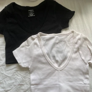 2-pack ribbade croppade toppar från Ambiance - Säljer två croppade ribbade toppar från Ambiance i svart och vitt. Båda har djup v-ringning och korta ärmar. Perfekta att matcha med jeans eller kjol. Storlek S/M men funkar även som XS/S