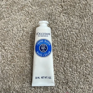 L'Occitane handkräm med sheasmör - L'Occitane handkräm med 20% sheasmör i en vit tub på 30 ml. Tuben har blå och silverdetaljer och är perfekt att ha i väskan. Ger intensiv återfuktning till torra händer och har en mild, fräsch doft.