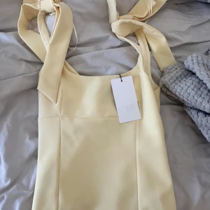 Ljusgul topp med rosettband från Zara - Supersöt ljusgul topp från Zara med breda axelband som knyts i stora rosetter. Figurnära passform och fyrkantig ringning. 