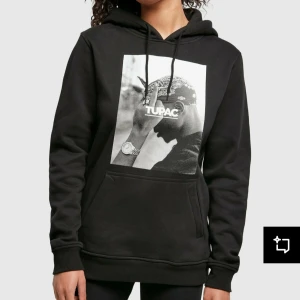 Svart Tupac hoodie från Mister Tee - Svart hoodie med stort vitt/svart Tupac-print på bröstet från Mister Tee. Tröjan har huva med dragsko och en stor magficka. Knappt använd, mycket mjuk.