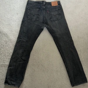 Svart/mörkgrå Levi's 501 jeans - Säljer ett par svarta-mörkgrå Levi's 501 jeans med klassisk rak passform. Perfekta för dig som gillar en tidlös stil med vintagekänsla.
