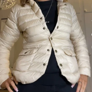 Beige pufferjacka med knappar - Säljer en beige pufferjacka med knappar framtill och två fickor med lock.  Köpt secondhand, säljs inte . STORLEK - S ( 36/38) den enda skadan finns på bild (sista bilden ) Priset kan diskuteras 