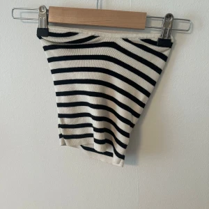 Randig tubtopp i stickat material - Säljer en stickad tubtopp med svarta och vita ränder. Toppen är ärmlös och säljer för den inte kommer till användning.