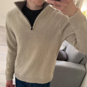 Beige stickad tröja med dragkedja från Eddie Bauer - Säljer en beige stickad tröja från Eddie Bauer med hög krage och dragkedja framtill. Perfekt för lager-på-lager och passar till många olika stilar. Klassisk och tidlös design. 183 62KG