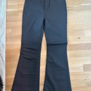 Mörkbruna bootcut-byxor från ASOS DESIGN - Säljer ett par mörkbruna faux lether -byxor från Asos. Aldrig använda, är stretchiga i storleken. Bra längd på mig som är 164