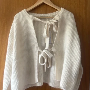 Vit stickad kofta med knyt från Gina Tricot - Superfin vit stickad kofta från Gina Tricot med två knytband framtill. Koftan har lång ärm och är mjuk och mysig, perfekt för lager-på-lager. Enkel att styla till olika outfits.