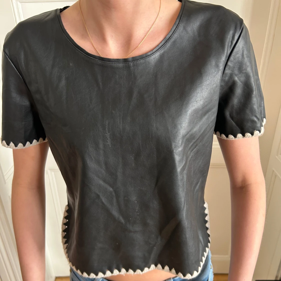 Svart skinnliknande topp med sicksack-detaljer - 1