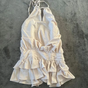 Ljusbeige volangklänning med pärldetalj - Supersöt ljusbeige kortklänning med volanger och pärlor vid halsringningen. Klänningen är köpt för ett par veckor sen och är aldrig använd. Säljer därför att den var fel storlek och passade inte mig i smaken. Köpt för 299 (på rea) säljer för 200. Tvättas såklart innan den skickas. Kom gärna med prisförslag❣️ 